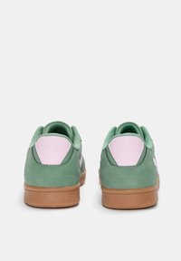 Baskets vertes et roses avec une finition en daim, dotées d'un arrière doux et texturé ainsi que d'une semelle en gomme pour l'adhérence et la durabilité.