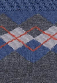 Strickpullover mit einem blau-grauen Argyle-Muster und roten Akzenten, strukturiertem Stoff und einem gerippten Kragen.