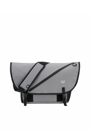 Bolsa de mensajero CAT gris con ribete negro, correa de hombro ajustable, bolsillo frontal con cremallera y cierre con solapa y dos hebillas.