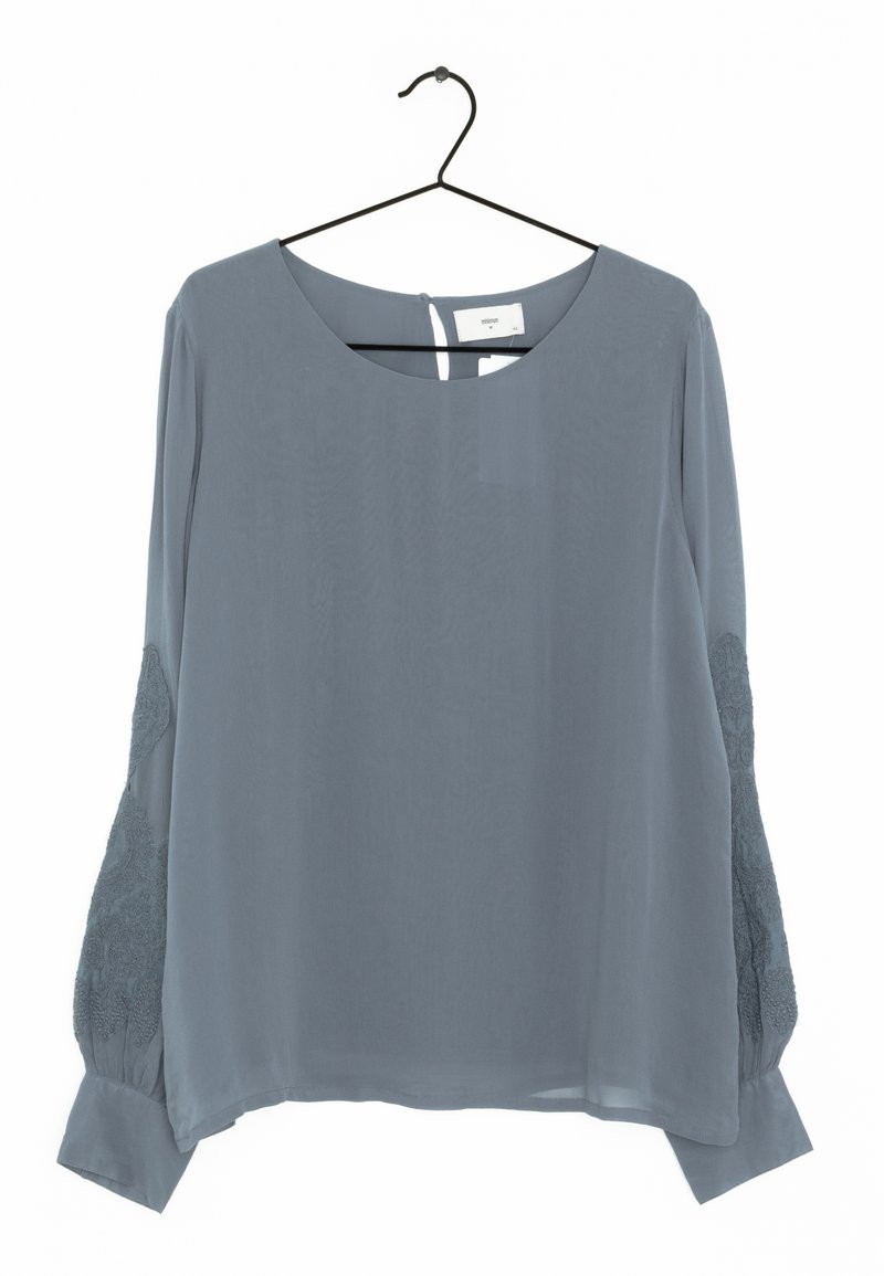Blusa a maniche lunghe in morbido tessuto grigio, con dettagli in pizzo sulle maniche, scollatura rotonda e chiusura con bottoni sul retro.