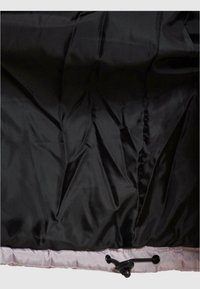 Tissu noir avec un ourlet cousu et un cordon de serrage noir réglable avec un bouton-pression sur une bordure gris clair, probablement une partie d'un vêtement ou d'un sac.