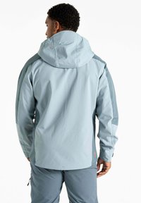 Veste imperméable bleu clair avec capuche ajustable, dotée de manches longues et d'accents de panneaux latéraux en bleu plus foncé. Vue arrière affichée.