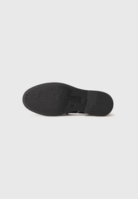 Black shoe sole with textured grip pattern and "Maria Corpetto" branding embossed in the center on a white background.