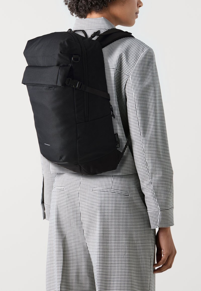 Black backpack with adjustable straps and front pocket, featuring a sleek, rectangular design and durable fabric texture.