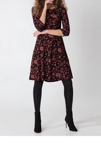 Black floral dress with three-quarter sleeves, featuring pink floral patterns, a flared skirt, and paired with black ankle boots and tights.