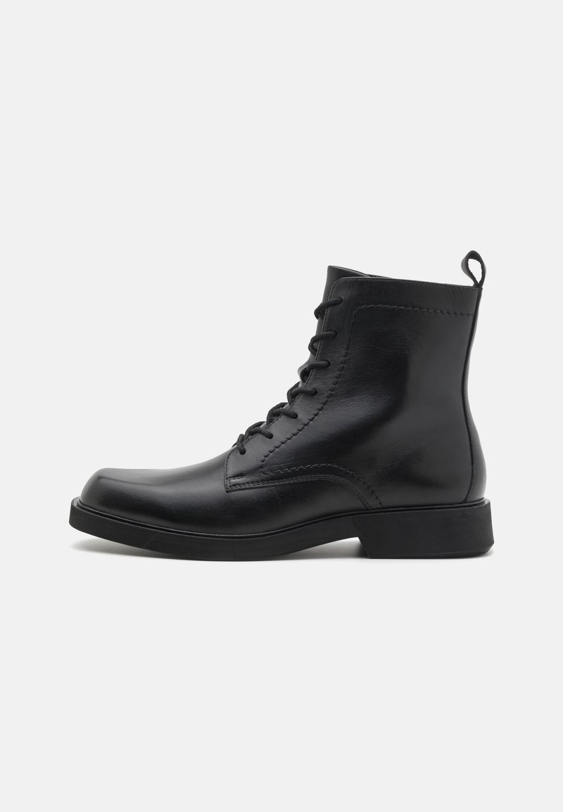 Bottines en cuir noir avec bout rond, lacets à l'avant et surface texturée. Comprend une languette à l'arrière et une semelle en caoutchouc solide pour une meilleure adhérence.