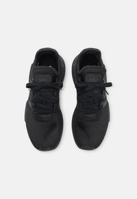 Zapatillas deportivas negras con parte superior de malla texturizada, cordones estrechos, suelas acolchadas y detalles de acentuación con el logo en la lengua.