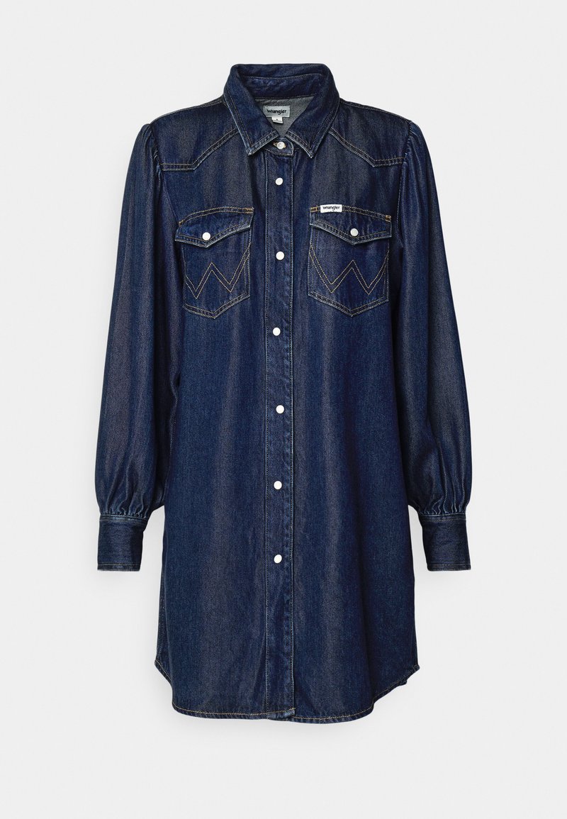 Robe chemise en denim bleu foncé avec un devant à boutons, deux poches poitrine, et des manches longues froncées avec des poignets. Détail de couture en zigzag subtil.