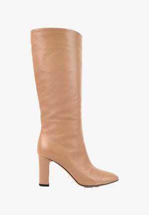 Botte en cuir beige montant jusqu'au genou avec bout pointu et talon bloc sur fond blanc.