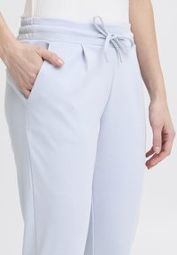 Ljusblå sweatpants i mjukt material, med dragsko i midjan, sidofickor och subtila veck framtill.