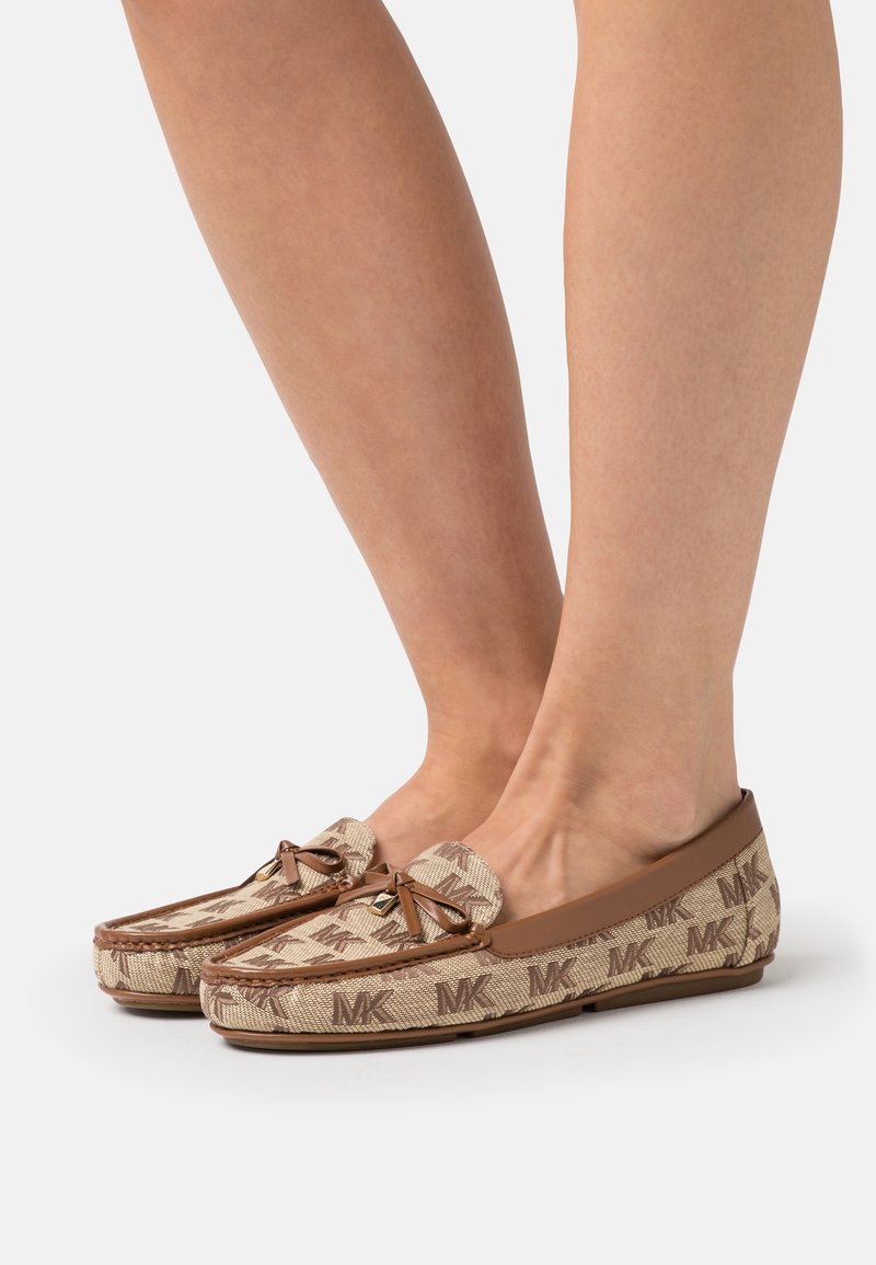 Mocassins marron et beige avec un motif texturé, présentant un détail en nœud, des bords en cuir et des accents de logo sur les côtés.