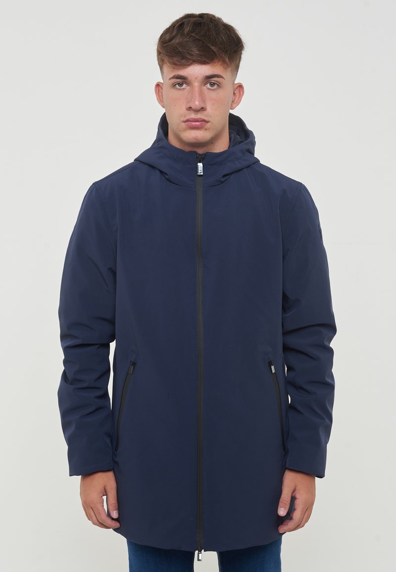 Giacca impermeabile navy in nylon, con cappuccio, zip frontale e tasche laterali con chiusura a zip. Tessuto liscio e taglio dritto.