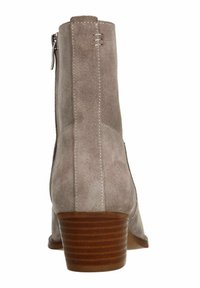 Beige suède enkellaars met een gestructureerd oppervlak, gestapelde houten hak en een ritssluiting aan de zijkant; gladde stiksels langs de naden.