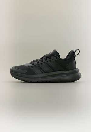 Sort atletiksneaker med mesh og syntetisk overdel, snørelukning, polstret krave og tyk polstret sål på en ensartet lys baggrund.