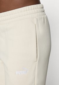 Krémové tepláky s elastickým pásom, s bielym logom "PUMA" a bočnou kapsou s hladkou textúrou.