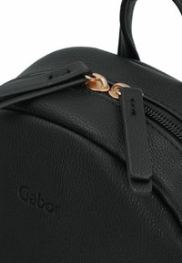 Sac à dos en cuir noir texturé avec une forme arrondie, dotée de ferrures en or rose et d'un logo de marque sur le devant. Détail de fermeture éclair visible.