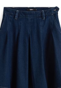 Jupe en denim foncé avec taille haute, plis et poches latérales. Le tissu présente une texture lisse avec des détails de couture subtils.