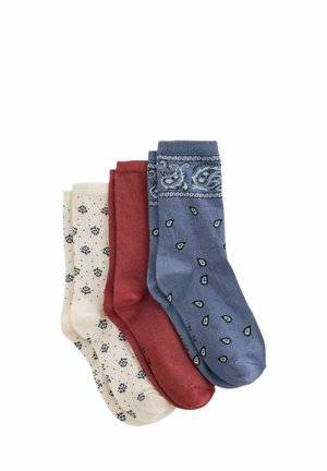 Trois paires de chaussettes mi-mollet pliées crème avec de petits motifs floraux foncés, rouge rouille uni et bleu avec des motifs cachemire et petites gouttes.