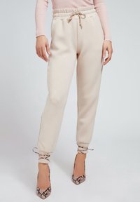 Krämfärgade, avsmalnande sweatpants med elastisk midja och snörning. Har avslutade fållar och mjuk textur.