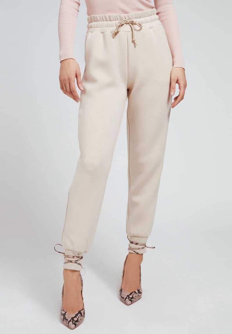 Krämfärgade, avsmalnande sweatpants med elastisk midja och snörning. Har avslutade fållar och mjuk textur.