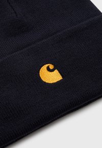 Berretto lavorato a maglia blu navy con una texture morbida, caratterizzato da un logo giallo ricamato a forma di spirale. Design con risvolto per maggiore calore e stile.