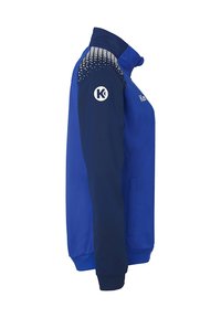 Blaues Sportjacke mit einem Reißverschlusskragen, kontrastierenden marineblauen Ärmeln, geometrischen Musterakzenten auf den Schultern und Logodetail am Arm.