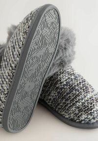 Strukturerede grå og sorte vævede hjemmesko med en faux fur manchet og mønstret gummisål med stjernemønstre.