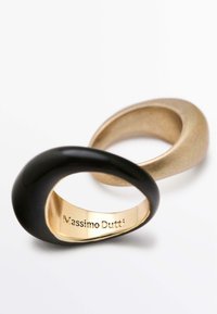 Due anelli: uno nero, liscio e lucido; l'altro oro opaco, con una forma arrotondata e scultorea. L'incisione interna recita "Massimo Dutti."