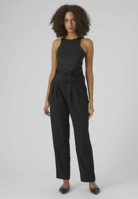 Haut sans manches noir avec des bretelles larges, assorti à un pantalon noir taille haute avec une ceinture et un design plissé à l'avant.