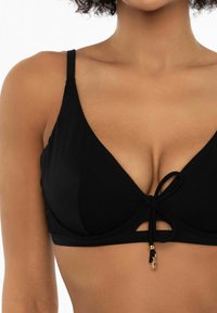 Czarny top bikini o fakturowanym wzorze, z regulowanymi ramiączkami, przednią kokardką oraz małym złotym ozdobnym elementem.