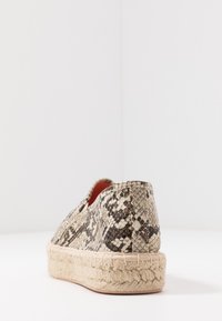 Espadrille-style shoe with a textured black and white snake print upper, beige espadrille sole, and a smooth red interior lining.