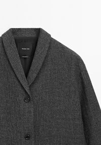 Szary wełniany płaszcz z kołnierzem typu szal, pojedynczym zapięciem na guzik i teksturowanym materiałem. Wewnątrz kołnierza znajduje się czarna metka.