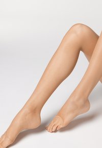 Collants transparents nus sur les jambes, avec une texture lisse, un léger éclat et un design avec pieds à finition translucide.