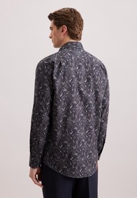 Camicia a maniche lunghe di colore blu scuro con un intricato motivo floreale bianco e grigio. Presenta polsini abbottonati e colletto classico.