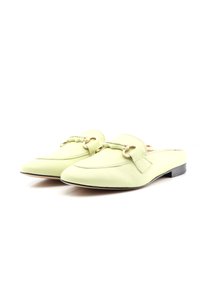 Světlé zelené kožené muly s kulatými špičkami, dekorativním páskem a zlatými detaily. Mají nízký černý podpatek a hladký povrch.