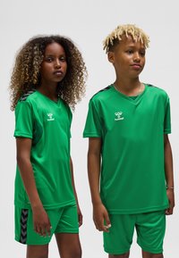 Grönt sportställ bestående av kortärmade tröjor och shorts. Har svarta detaljer på axlar och sidor, tillverkat av lätt material.