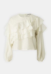 Blouse crème avec des volants en cascade, des manches bouffantes longues et un col rond. Fabriquée en tissu léger et texturé.