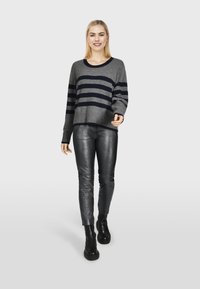 Grijs gestreepte trui met marineblauwe strepen, losse pasvorm, geribbelde manchetten; gecombineerd met aansluitende zwarte leren broek en zwarte chunky enkelboots.
