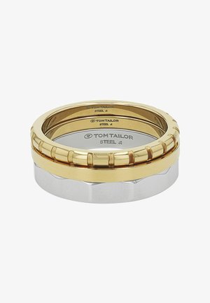 Tres anillos apilados en tonos dorados y plateados con la marca Tom Tailor grabada en el interior de cada anillo.