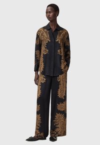 Mustmustest mustriided, millel on kuldne paisleimuster; pika varrukaga särk, millele on lisatud krae, ja sobivad laiad püksid; minimalistlikud mustad jalanõud.