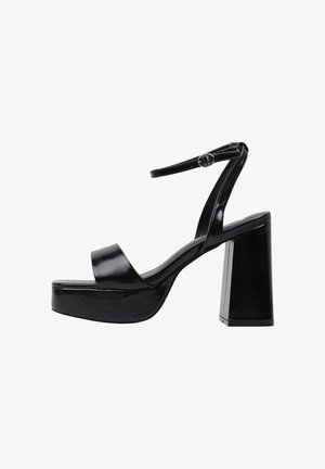 Sandalias de plataforma negras de tacón alto con un acabado brillante, que cuentan con una amplia correa frontal y una delgada correa en el tobillo asegurada por una hebilla de metal.