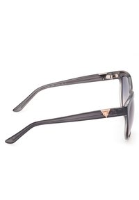 Gafas de sol de plástico gris con lentes degradados, un marco cuadrado elegante y un acento triangular en oro rosa en las patillas.