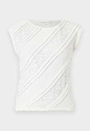 Haut blanc sans manches avec des panneaux en dentelle diagonale et des détails de bordure texturée sur un fond plat et neutre.