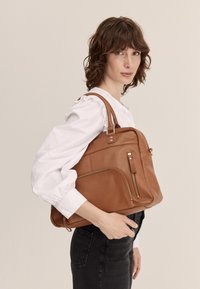 Borsa a mano in pelle marrone con una forma strutturata, manici superiori e tasche con zip, completata da dettagli in metallo dorato e una finitura testurizzata.