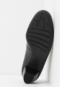 Schwarzer Lederschuh mit einer strukturierten Gummisohle, ausgestattet mit einem niedrigen Absatz und einem gerillten Muster für besseren Halt. Markenname "Gabor" sichtbar.