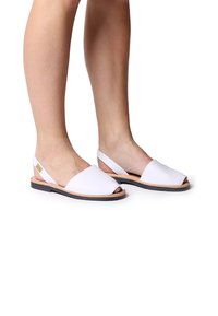 Vita öppen tå slingback sandaler med en mjuk läderöverdel, brun läderinläggssula och svart gummisula; enkel design med sidoremsa.