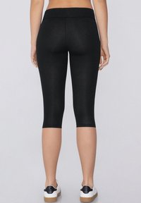Leggings capri noirs en tissu extensible, avec une taille lisse et une coupe ajustée se terminant juste sous le genou.