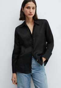 Sort linned skjorte med langeærmer, knaplukning og klassisk krave; parret med lyseblå denim jeans.