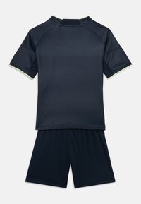Completo sportivo blu scuro composto da una maglietta a maniche corte con righe orizzontali e pantaloni corti abbinati. Accentuato da dettagli in verde chiaro.