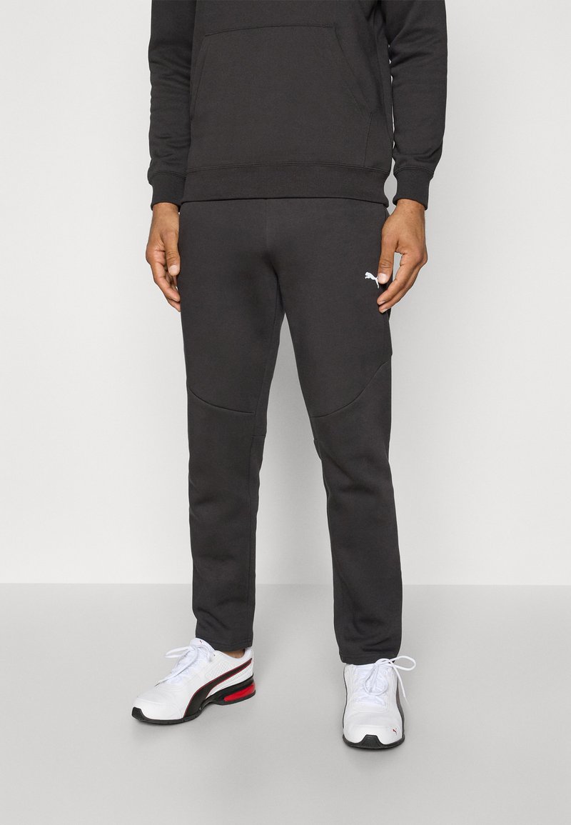 Sort sweatshirt med kængurulomme, sammensat med mørke sweatpants med sidelommer, begge lavet af blødt stof. Hvide logoaccente.